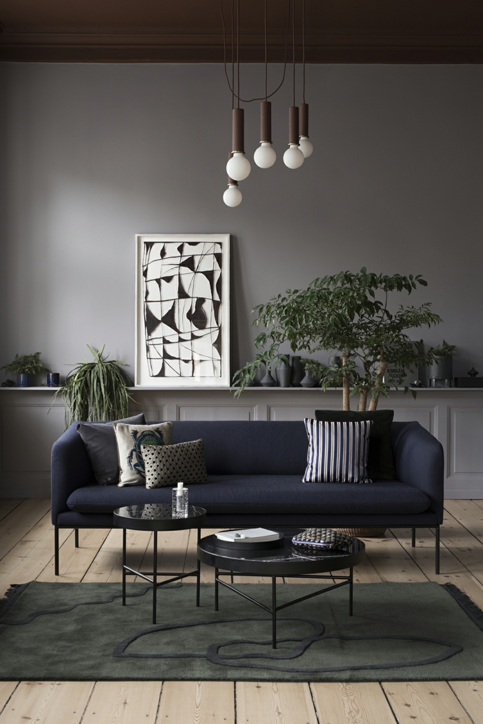 ideas de decoracion moderna, salon con suelo de tarima, sofá tapizado azul navy, habitacion gris, tapete, mesitas bajas redondas, cuadro en blanco y negro