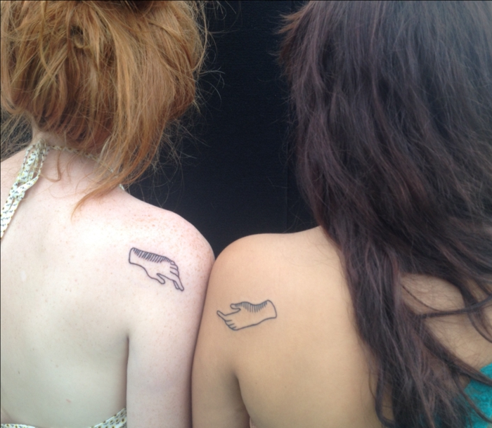 tatuajes de hermanas, idea de diseño de tatuajes iguales en el hombro, pequeñas manos abiertas una hacia la otra, mujer morena, mujer pelirroja