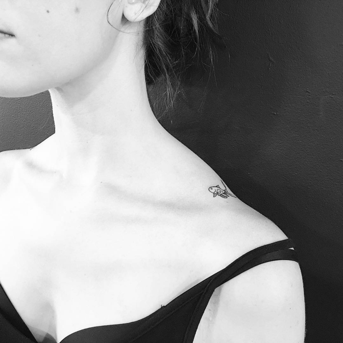 foto blanco y negro, tatuaje pequeño de pez en el hombro, mujer con escote y pelo recogido, tatuajes elegantes