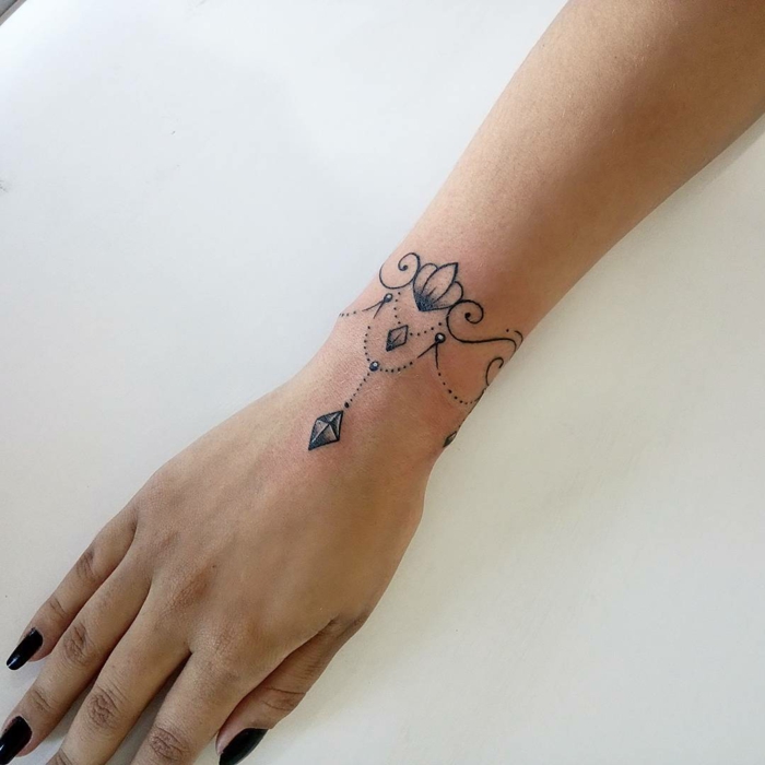 tatuaje para mujeres tipo joyería con adornos estilo oriental, tatuaje infinito, mano femenina con uñas pintadas