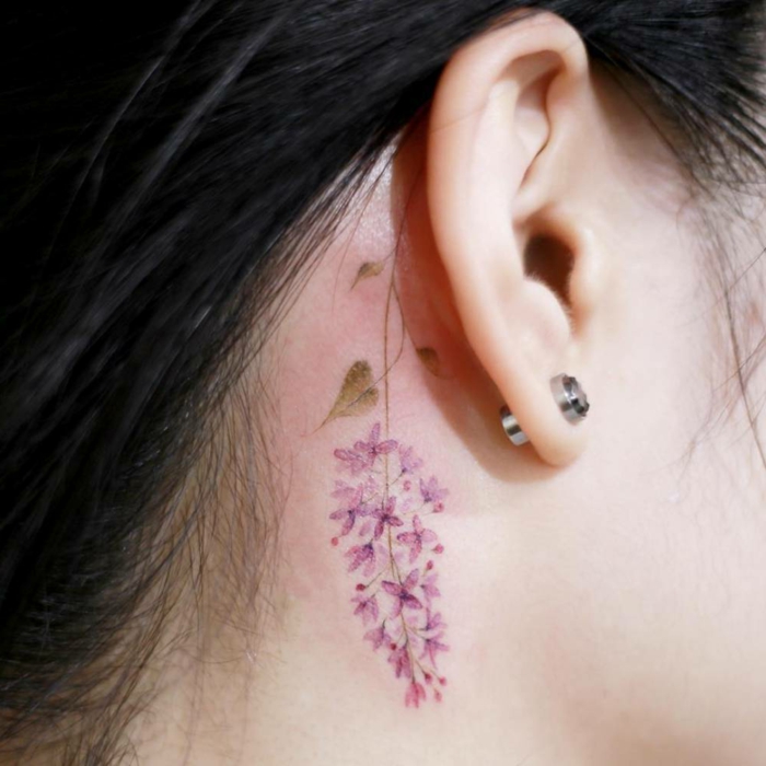 tatuaje de flores detrás de la oreja, mujer con pendientes, flor morada, tatuaje acuarela, tatuajes pequeños
