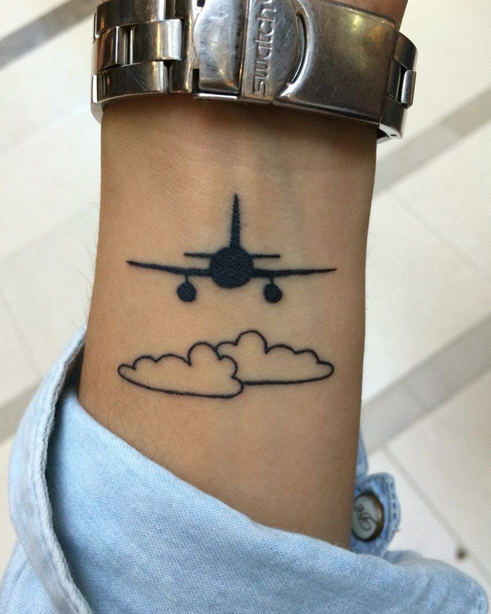 tatuaje estilo animación, mano con reloj y camisa jeans, avion volando sobre nubes, blanco y negro, tatuajes originales