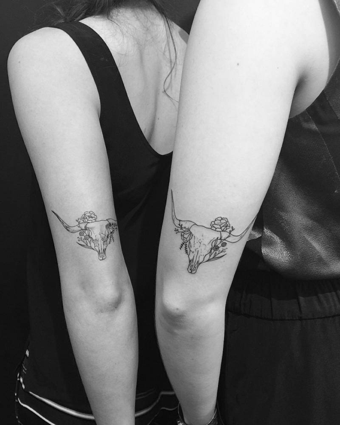 tattoo hermanos, idea de tatuajes iguales en el brazo, cráneo de toro en blanco y negro con flores, idea de tatuajes para hermanas o mejores amigas, foto en blanco y negro