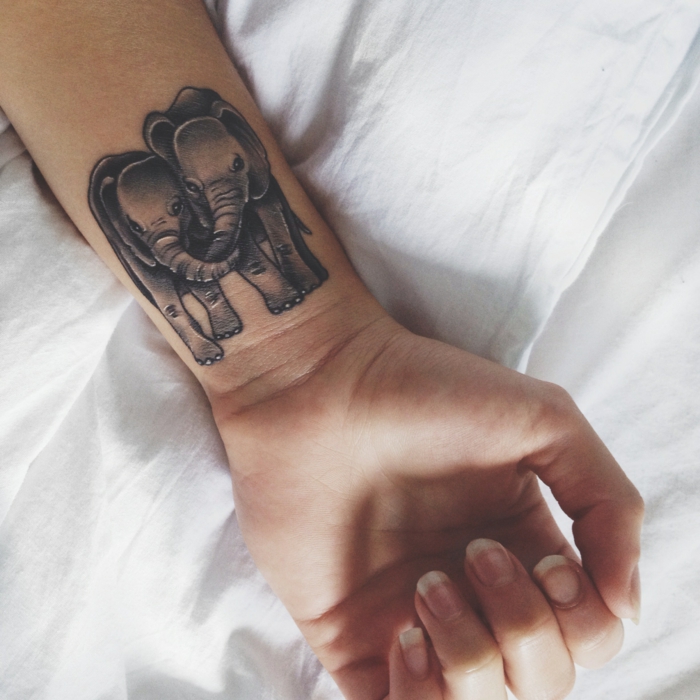 tatuaje de elefantes enamorados, tattoo en la muñeca, diseño femenino, mano con uñas largas de mujer
