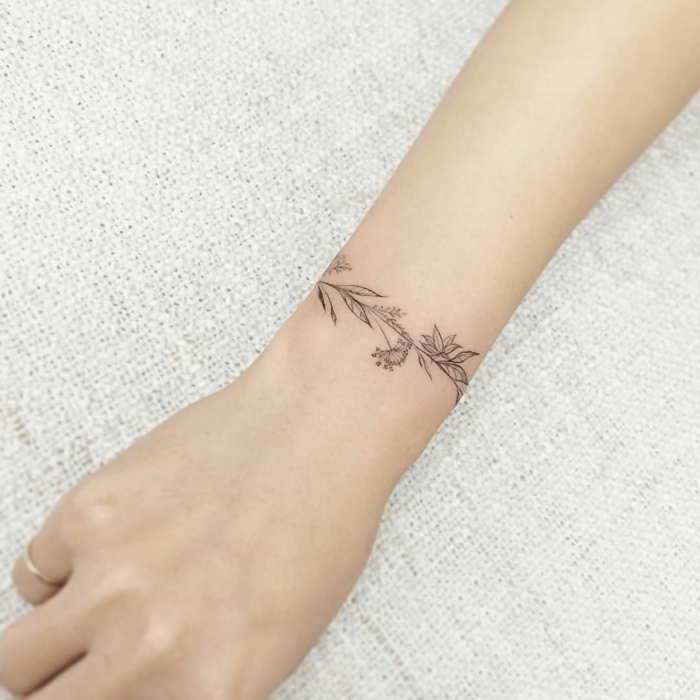 mano delgada, diseño tatuaje brazalete minimalista, motivos florales para mujeres, tatuajes muñeca, mano con anillo