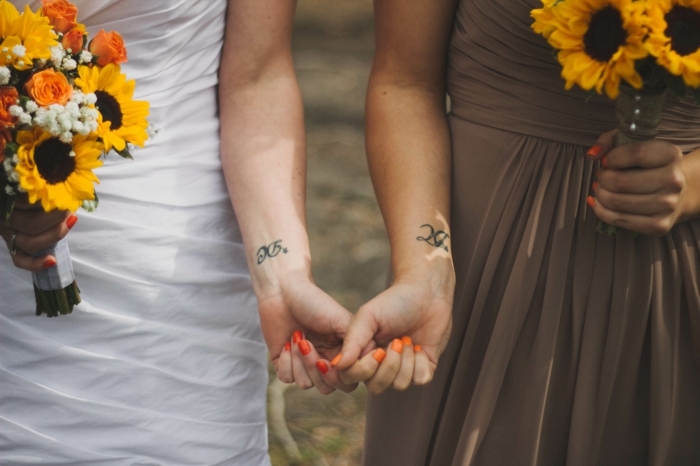 muñecas tatuadas con iniciales, mujeres con ramos de girasoles, uñas color naranja, tatuajes familia simbolos