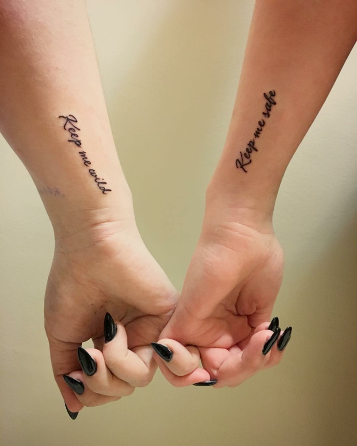 idea de tatuajes de frases para amigas, manos femeninas con uñas pintadas de negro, tatuaje en la parte lateral de la muñeca, frase motivadora en cursiva, tatuajes pequeños originales