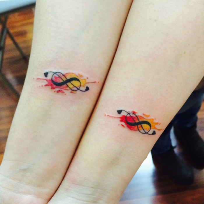 idea de tatuaje para parejas o amigos, signo de infinito negro con manchas de color amarillo y rojo, tatuajes muñeca