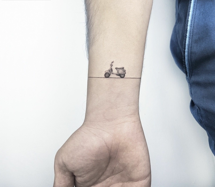 hombre con muñeca tatuada, tatuaje tipo brazalete con scooter vespa pequeño, mini tatuajes, diseño único