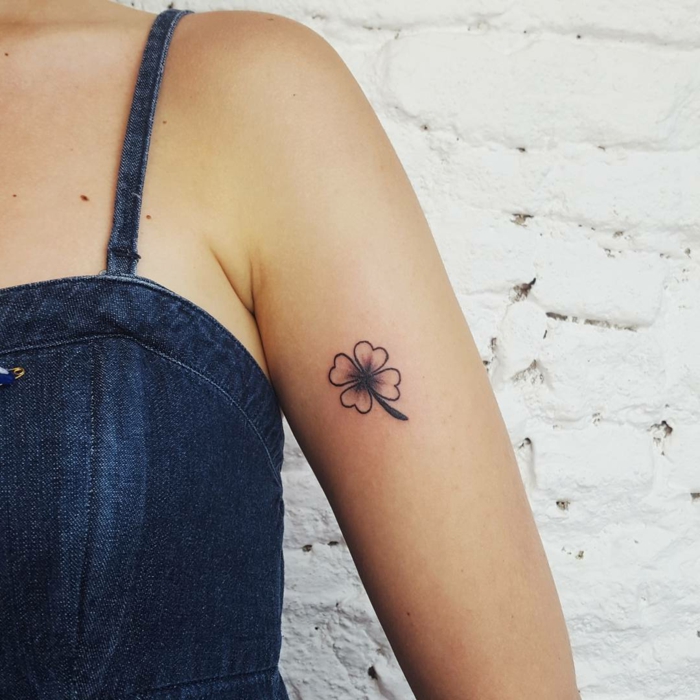 mujer con vestido de jeans, tatuaje pequeño en el brazo, trébol de cuatro hojas, tatuajes simbolicos