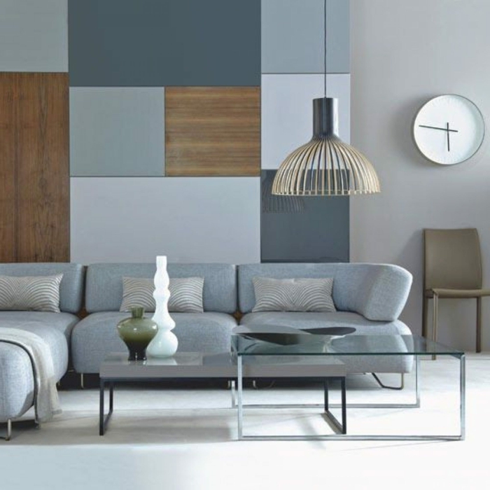estilo nordico, pared decorada con paneles en tonos grises, mesita de vidrio, reloj redondo, lámpara colgante, decoracion habitacion