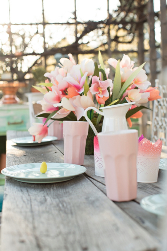 centro de mesa en colores pastel, bonita decoración de flores y pequeños huevos pintados en amarillo, jarrones en color rosa 