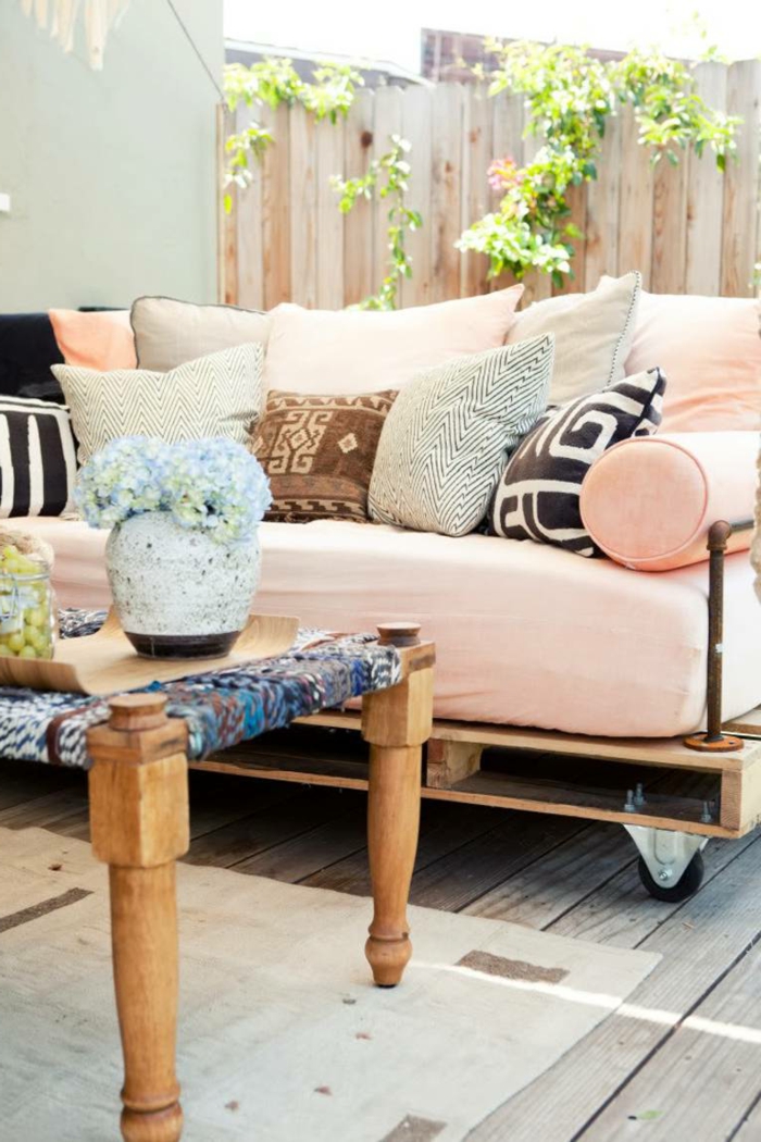 ideas de encanto de decoracion con palets, sofá en color rosa hecha de palets de madera, cojines decorativos con estampados