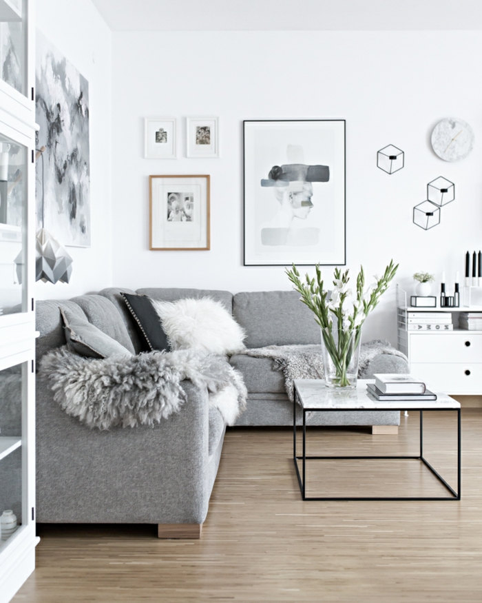 decoracion de salones en estilo nórdico, sofá en gris plata con cojines decorativos en blanco y negro, paredes en blanco con cuadros decorativos