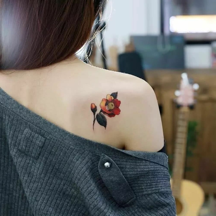 ejemplos de tatoos pequeños en la espalda, detalle bonito tatuado en la espalda, tatuaje de flor en rojo y amarillo 