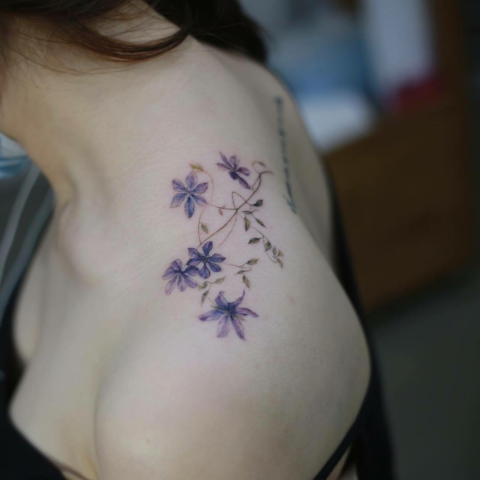 tatoos pequeños con motivos florales, precioso tatuaje en color lila, bonita flor tatuada en el hombro 