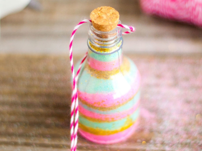 propuestas para hacer manualidades con botellas de cristal, pequeña botella de vidrio decorada con purpurina en verde, dorado y rosado 