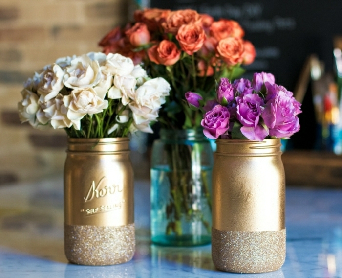 bonitas ideas sobre como decorar botes de cristal, botes pintados en dorado con decoración de purpurina, preciosos jarrones de flores DIY