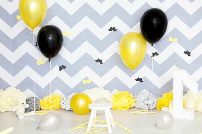 decoración de fiestas con globos brillantes en amarillo y negro, pared con papel pintado en blanco y gris, 