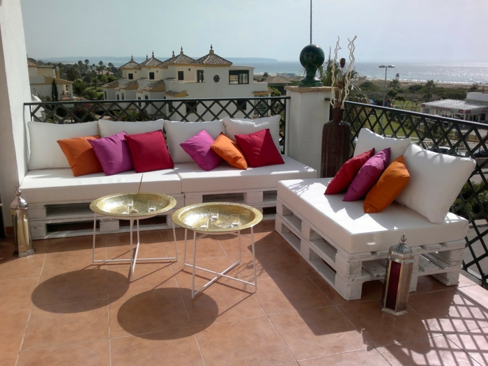 terraza moderna con bonita vista al mar, decoracion con palets y cojines decorativos en rojo, rosado y naranja