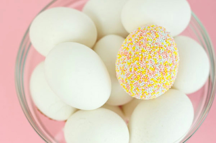 huevos blanco decorados con bolas de azúcar en colores pastel, huevo en amarillo verde y rojo 