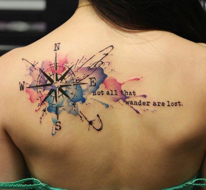 grande tatuaje con pintura acuarela, ideas de tatuajes espalda mujer, brújula con letras y colores 
