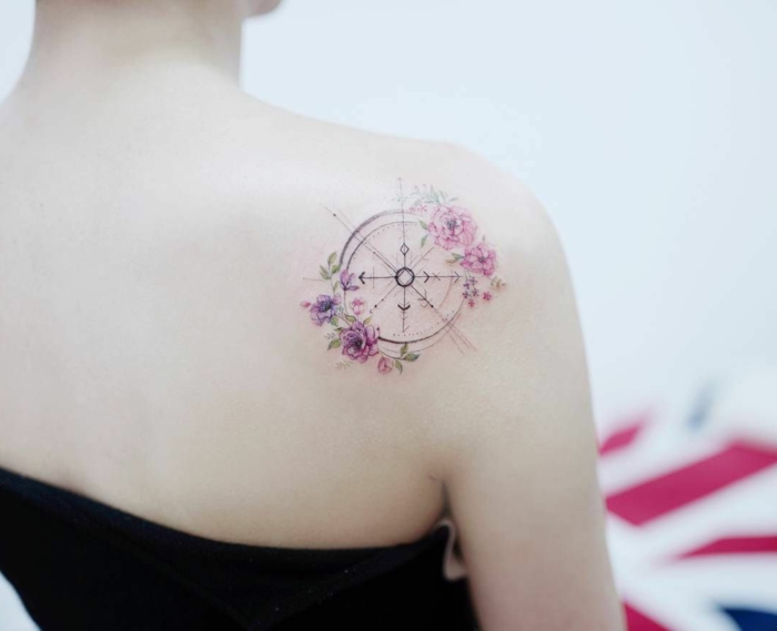 preciosa brújula decorada de flores en rosado y lila, ejemplos espectaculares de tatuajes espalda mujer