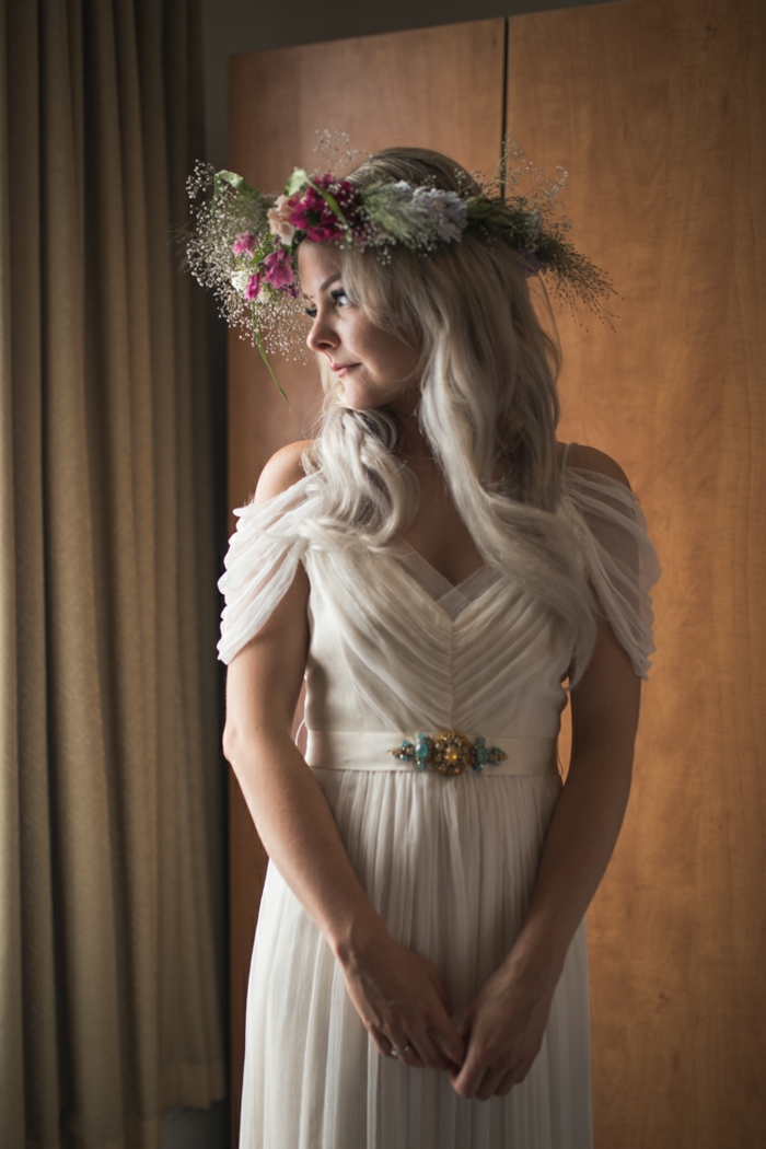 vestido de novia de tul con mangas sueltas en color marfil, pelo suelto ondulado y tiara de flores coloridos 