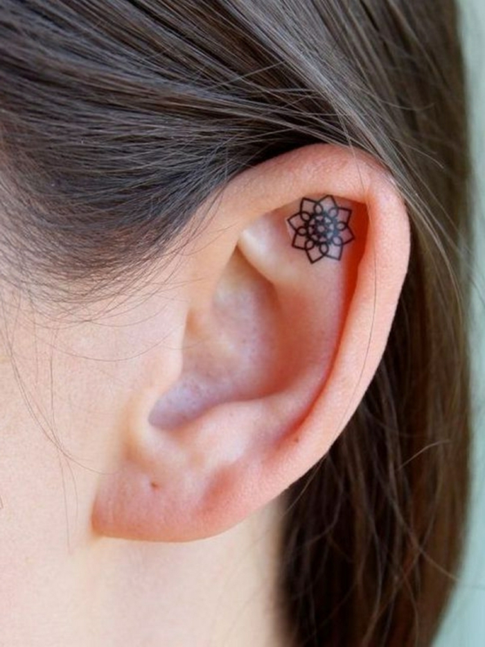 diseños de tatuajes modernos, tatuaje en la oreja en estilo minimalista, pequeña mandala dibujada con tinte negro