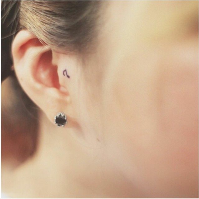 tatuajes de mujer en estilo minimalista, pequeña nota musical dibujada en la oreja en negro, ideas de tatuajes con simbología