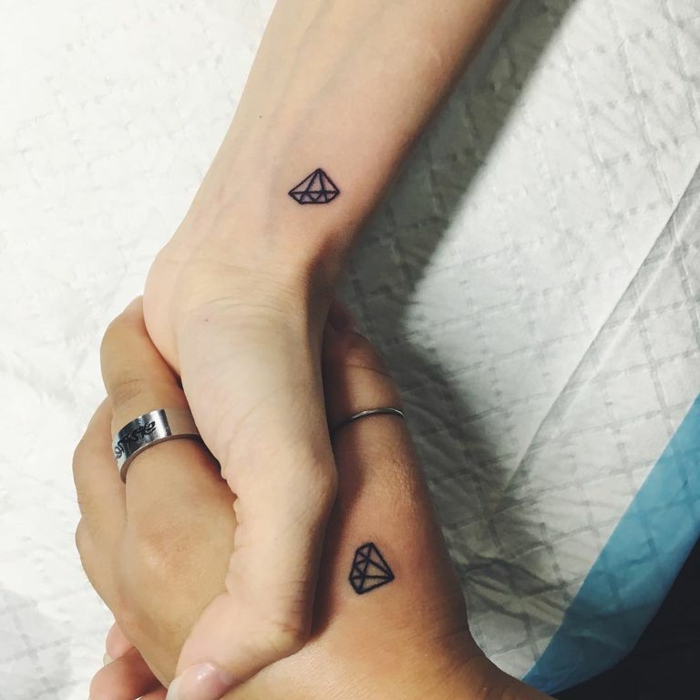 pequeños tatuajes antebrazo mujer en color negro, dos mujeres con tatuajes de pequeños diamantes en las manos