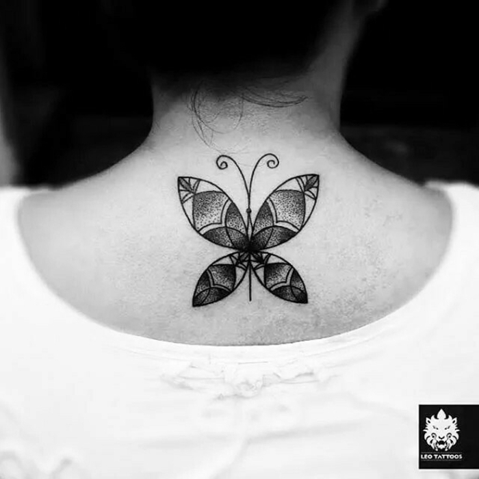 tatuajes de mujer con motivos geométricos, dibujo de mariposa con tinte negro tatuado en la parte superior de la espalda