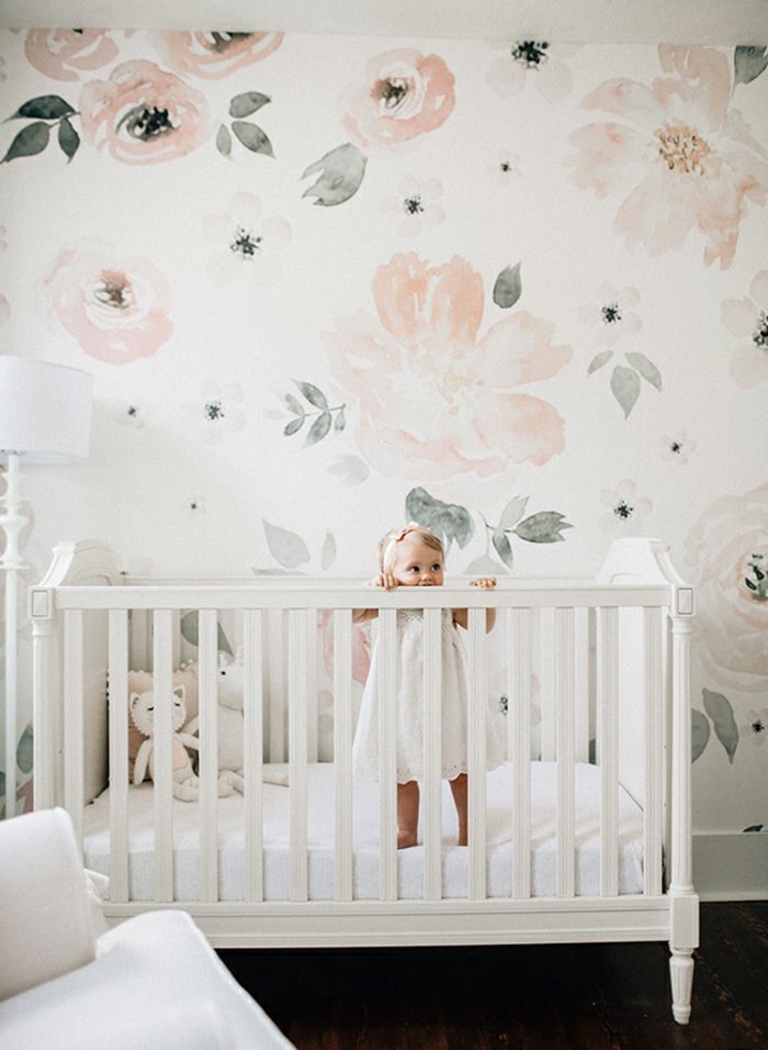 habitación decorada en colores pastel, paredes con papel pintado motivos florales, pequeña cama de madera en blanco