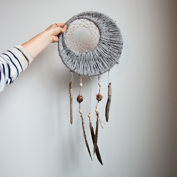 atrapasueños ganchillo original decorado de hilo en gris, palos de madera y plumas de halcón, manualidades para decorar la casa paso a paso 