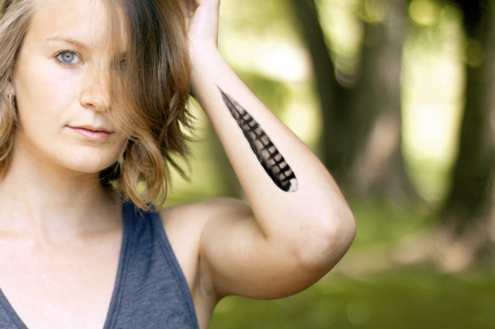 tatuaje de halcón en el antebrazo, ideas originales de tatuajes de plumas, mujer con tatuaje en blanco y negro 