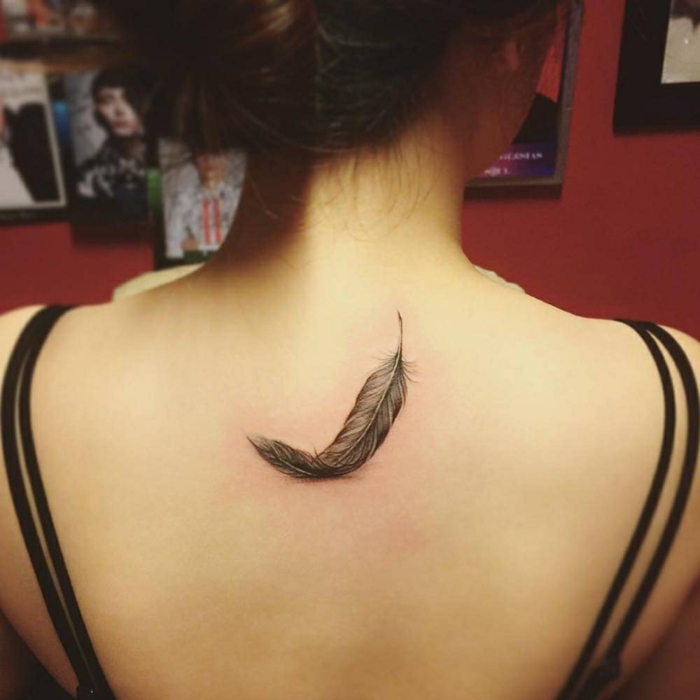 diseños de tatuajes de encanto, tatuajes para mujeres, pluma en negro en la espalda 