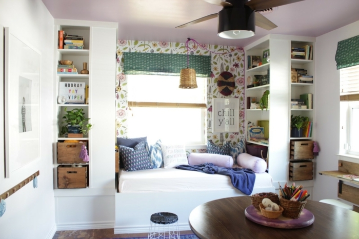 bonita habitación con partes de pared en papel pintado con motivos florales, cama cómoda con cojines decorativos 
