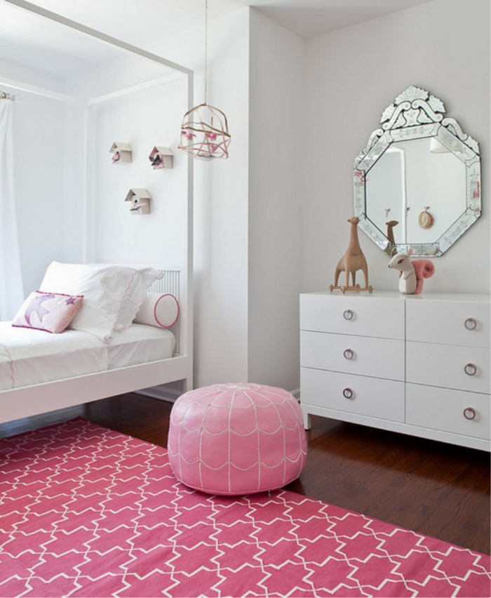 habitacion niñas en blanco con elementos en rosado, alfombra ornamentada y taburete de piel