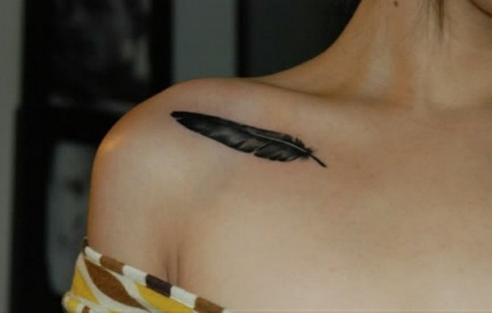 ideas de tatuajes pequeños para mujer delicados y bonito, pequeña pluma en el hombro con tinte negro, tatuajes con significado 2018 