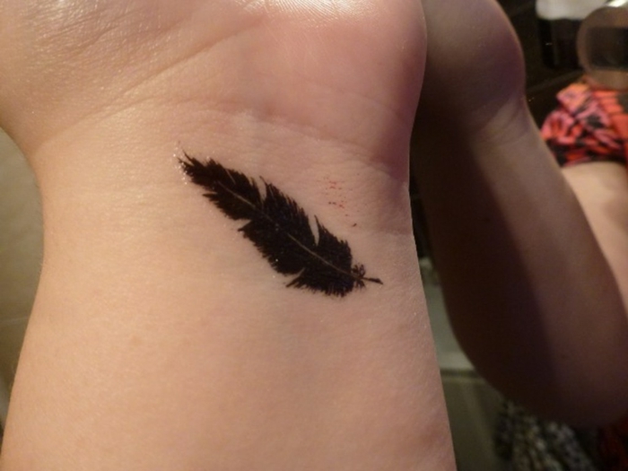ideas de tatuajes minimalistas plumas indias, pequeño tatuaje con pluma con tinte negro en el brazo 