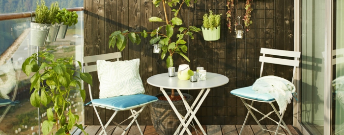 terrazas pequeñas con encanto, decoración minimalista con muchas plantas verdes, peque;a mesa oval y sillas plegables 