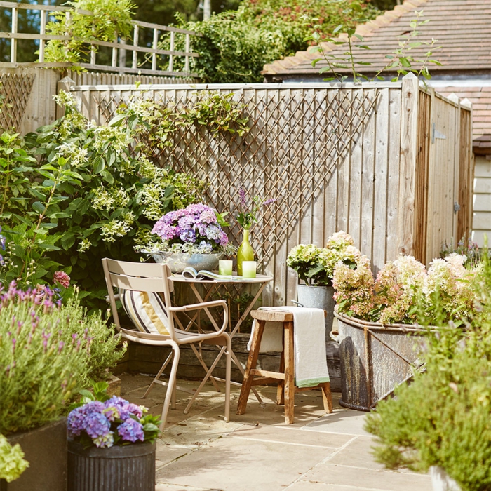 ejemplos de decoracion terrazas y patios, peque;as mesa y sillas de madera, plantas verdes con flores, patios decorados pequeños