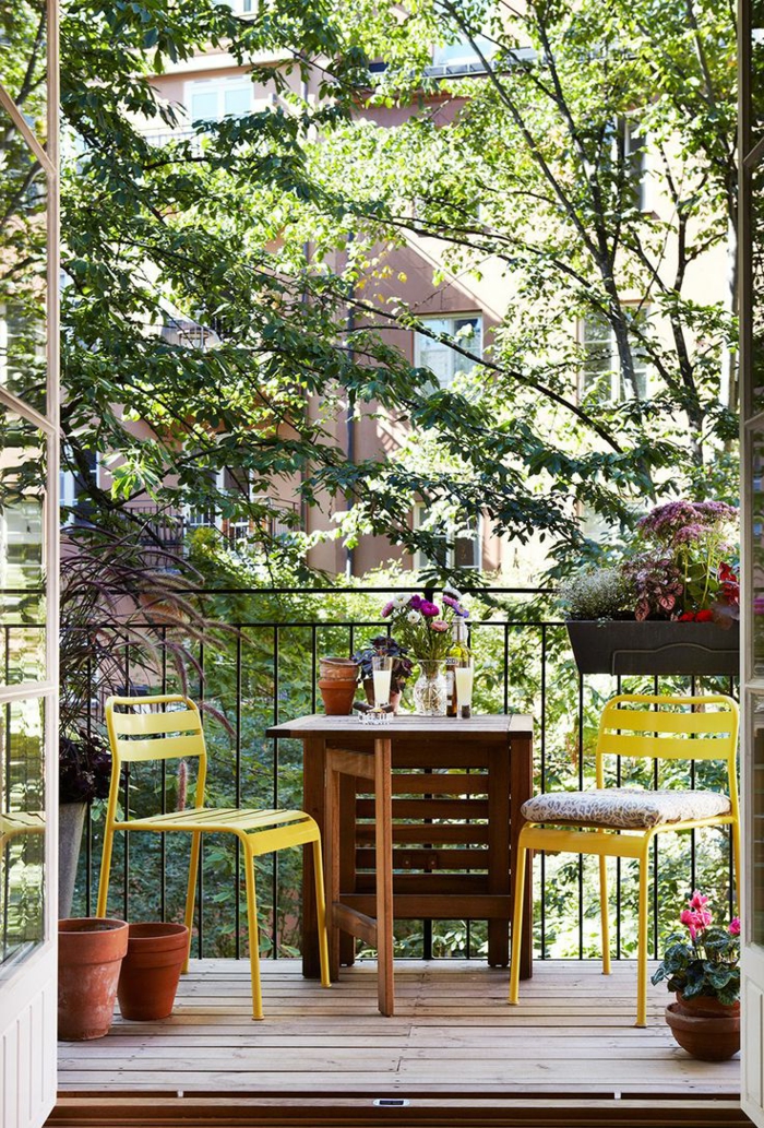 ideas de decoracion de terrazas y balcones pequeños, mesa de madera y dos sillas en color amarillo 