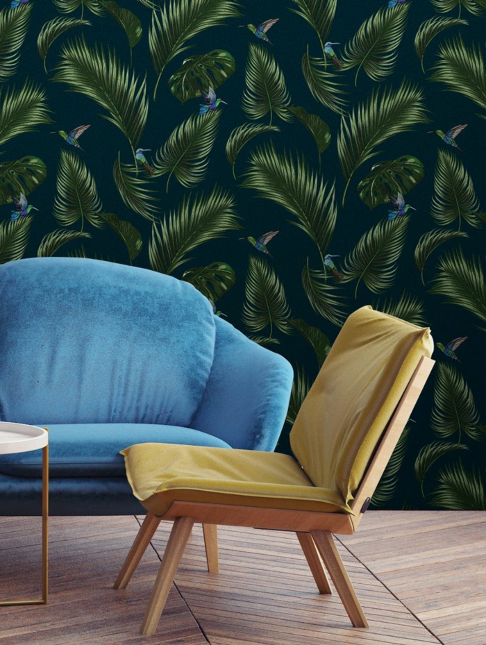 combinación de colores sofisticada, silla en color mostaza, sofá tapizada en azul y papel pintado habitacion con estampado de hojas 