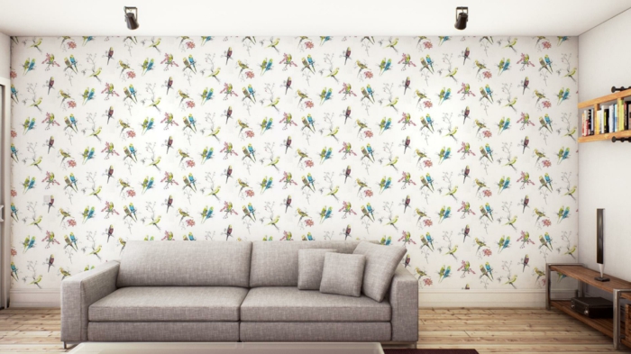 salón decorado en estilo minimalista con papel pintado en blanco y dibujos de aves, sofá en gris y suelo de parquet 