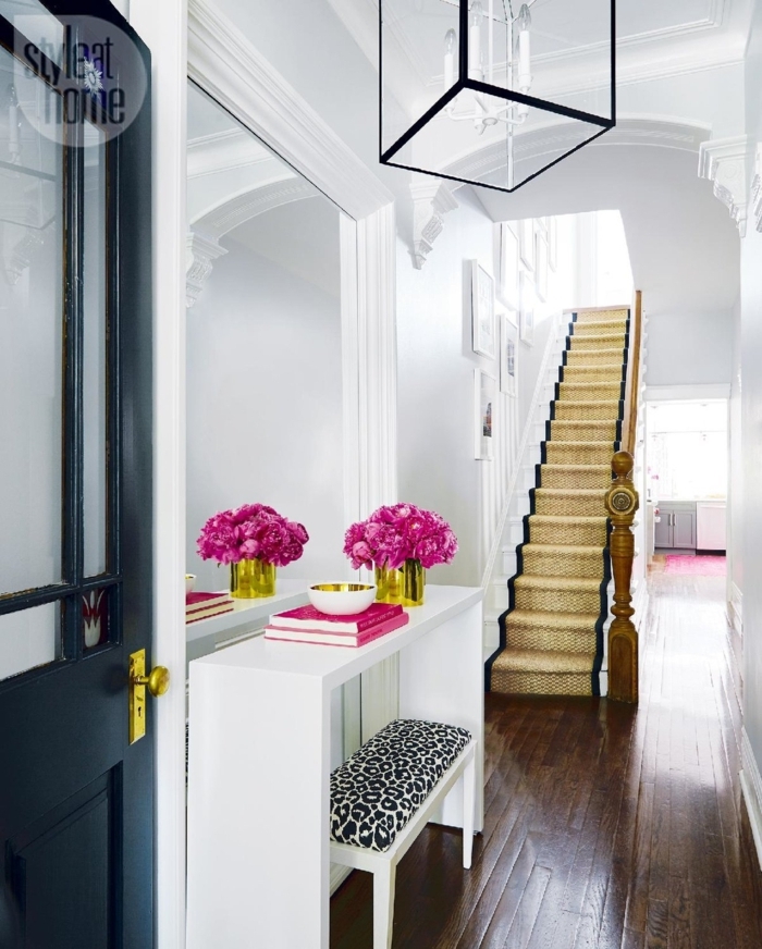decoracion sofisticada de un pasillo en blanco y negro con grandes escaleras y decoracion de flores, ideas para pintar pasillo moderno