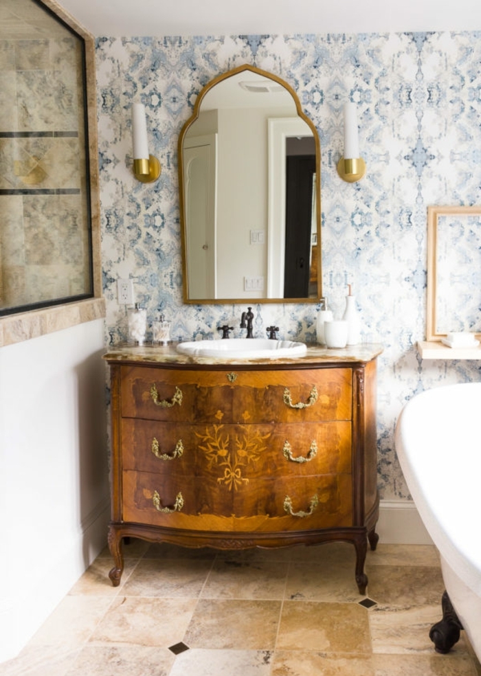 precioso baño en estilo vintage con papel decorativo para pared en azul y blanco, cofre oranamentado de madera y bañera patas garra