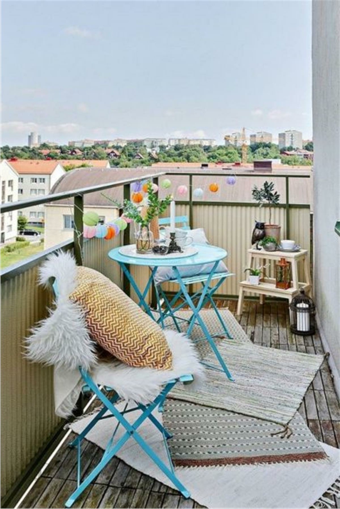 decoracion balcones pequeños colores claros, muebles plegables pintados en azul y alfombras en beige 