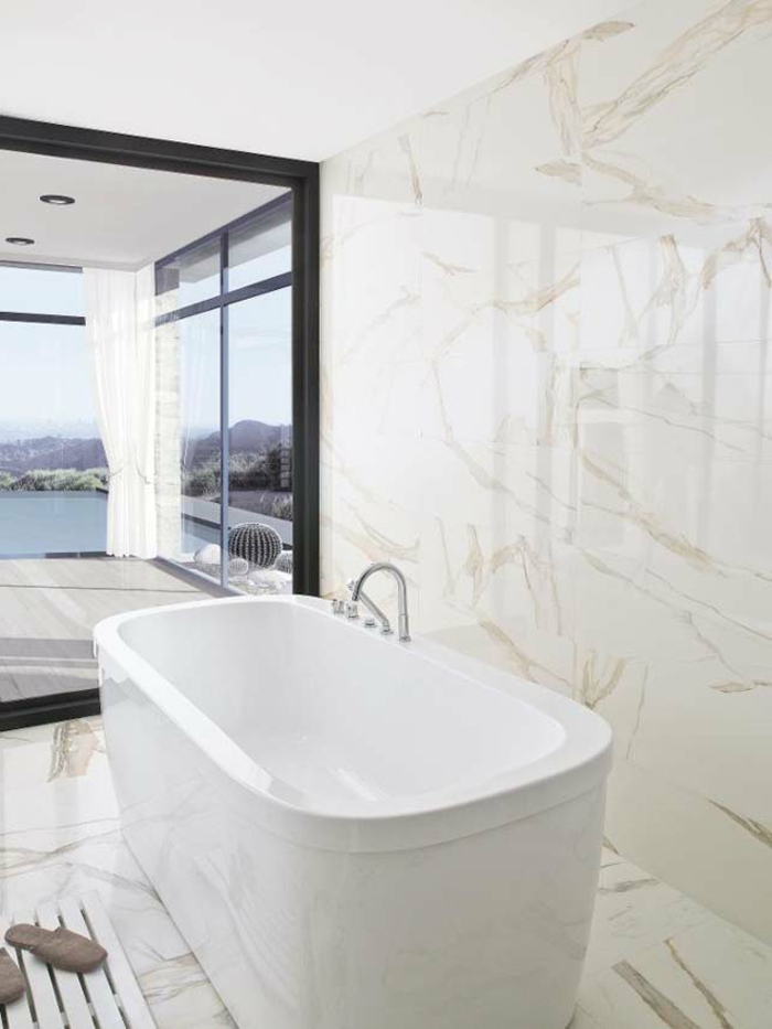 ejemplos de baños modernos con vista, bañera exenta en blanco y paredes y suelo baldosas de mármol 