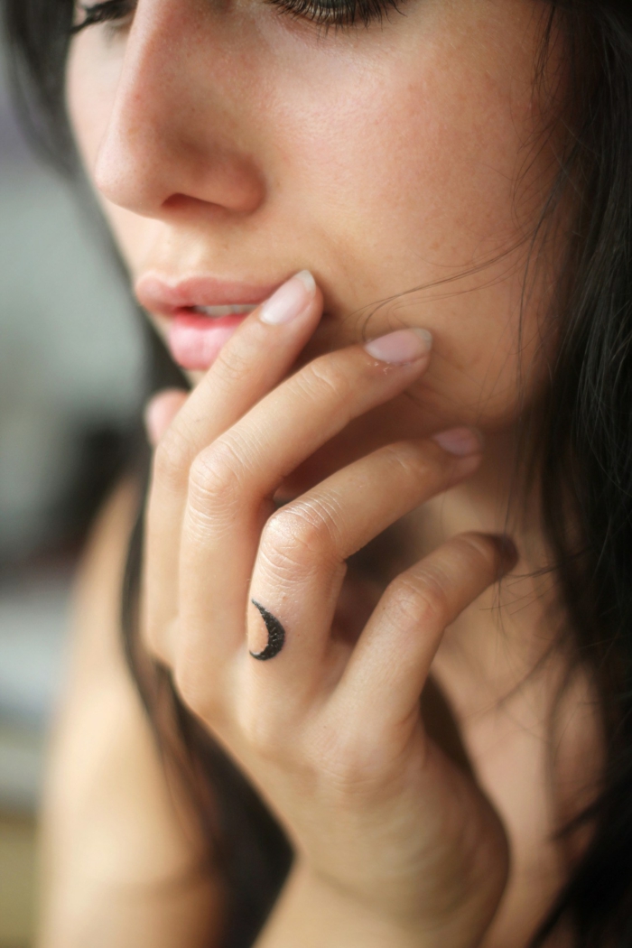 diseños de tatuajes finos para mujer con significado, pequeña luna con tinte negro tatuada en el dedo anular